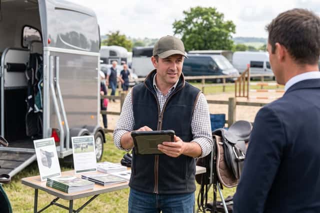 Venditore che mostra un annuncio su tablet a un cliente durante una fiera equestre